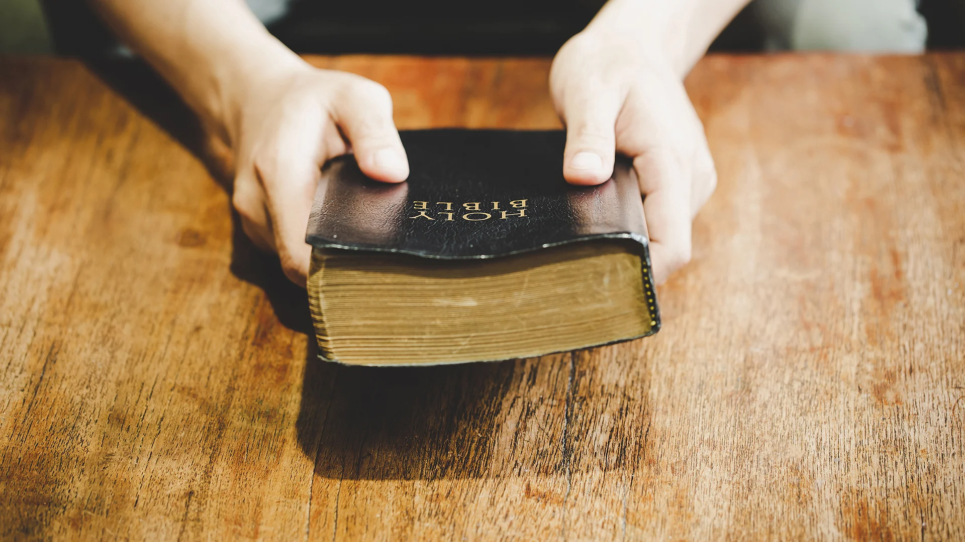 Hands folded in prayer on a Holy Bible in church