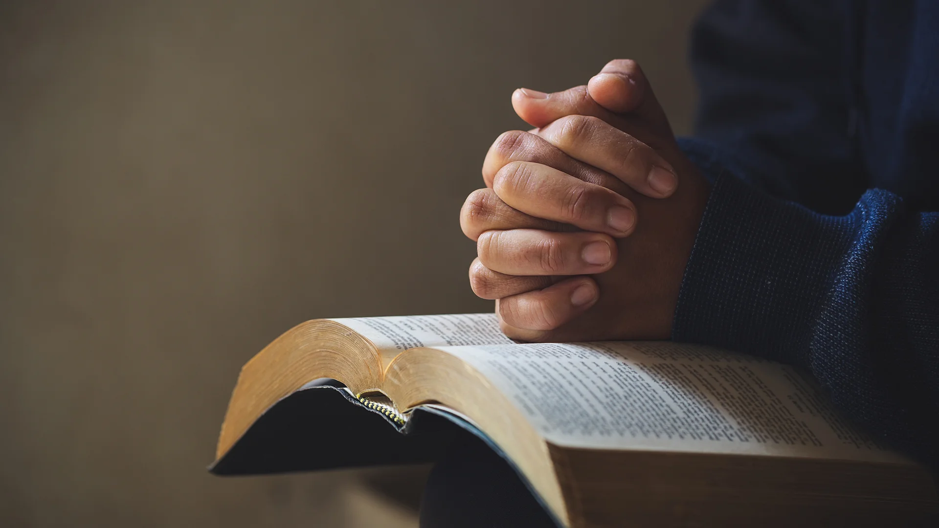 Hands folded in prayer on a Holy Bible